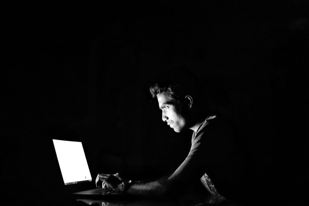 homem usando computador no escuro