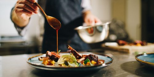The chef pouring special sauce on pork ribs in the kitchen